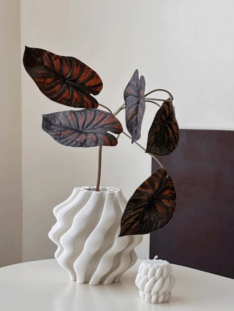 White 3D printed vase for plants with dark, textured leaves. Home decor.